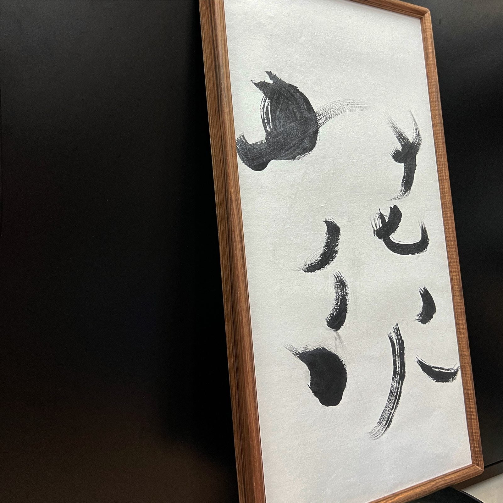 花火 — Fireworks. Sparse, explosive ink strokes in a walnut frame, leaning against a dark cabinet.
